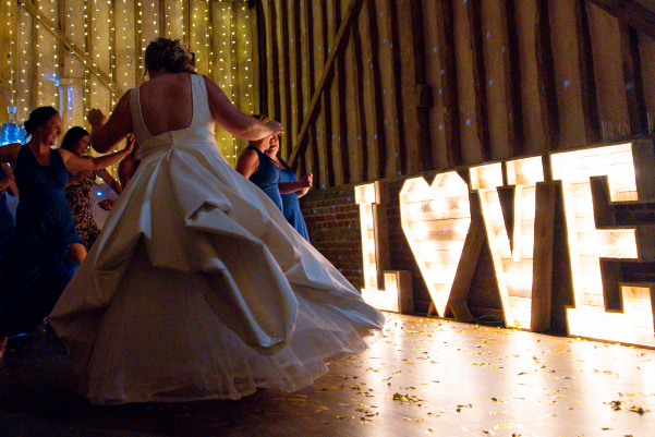 Wedding DJ at Lillibrooke Manor barn wedding venue in Berkshire - bride and groom dances with light up letters behind