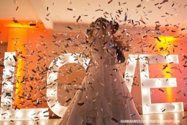 Wedding DJ at Stoke Place wedding venue in Buckinghamshire - couple standing in front of LED light up letters with confetti cannon