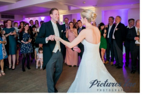 Wedding DJ at Stoke Place wedding venue in Buckinghamshire - couples first dance with happy guests in backdrop