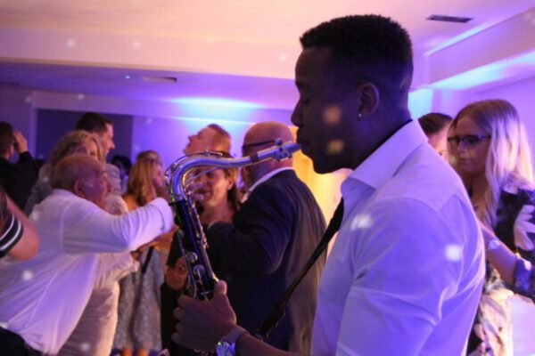 Wedding DJ at Stoke Place wedding venue in Buckinghamshire - guests dancing to sax player with DJ