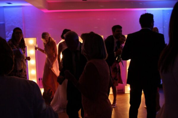 Wedding DJ at Stoke Place wedding venue in Buckinghamshire - guests dancing in front of LED light up letters