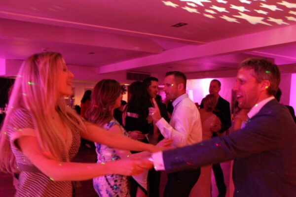 Wedding DJ at Stoke Place wedding venue in Buckinghamshire - pink mood lighting and dancing guests