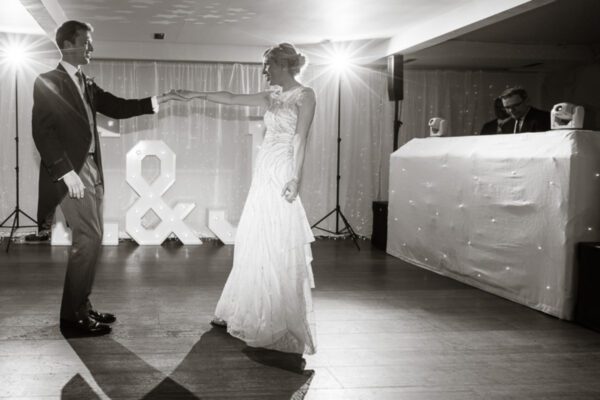 Wedding DJ at Stoke Place wedding venue in Buckinghamshire - bride and groom dancing in front of DJ booth and light up letters