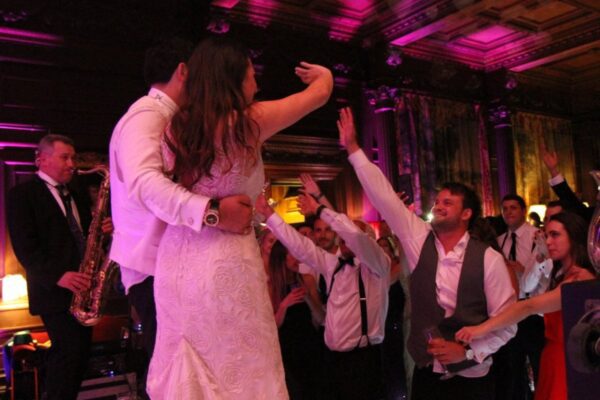 Wedding DJ at Cliveden House, Berkshire - wedding guests partying with bride and groom on stage with live wedding band